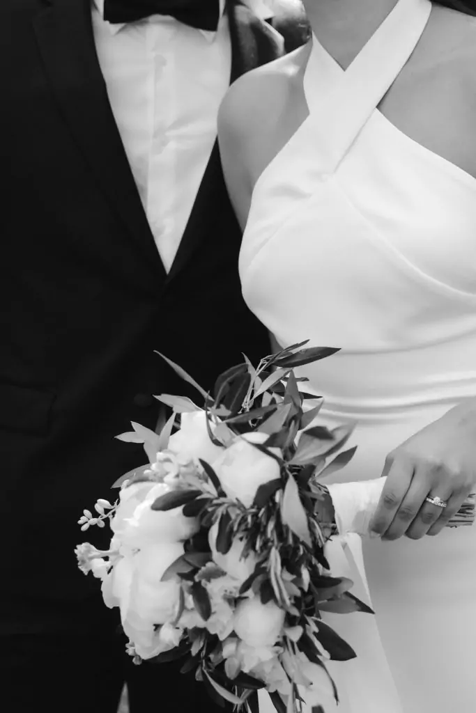 Brautpaar im schwarzen Anzug und eleganten Brautkleid mit einem Brautstrauß in Aachen