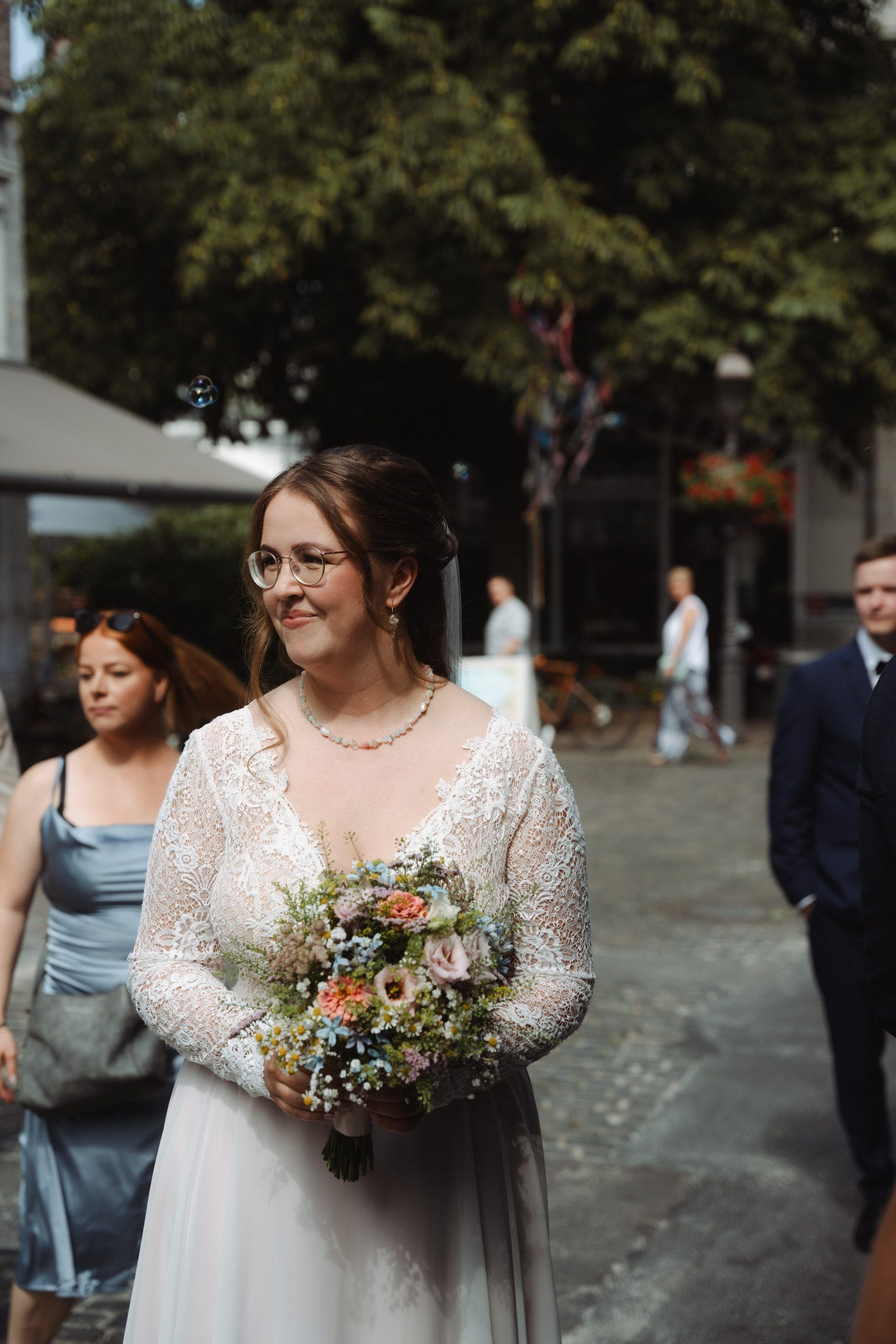 Braut mit Blumenstrauß vor dem Standesamt Zeitungsmuseum Aachen bei Sonnenschein