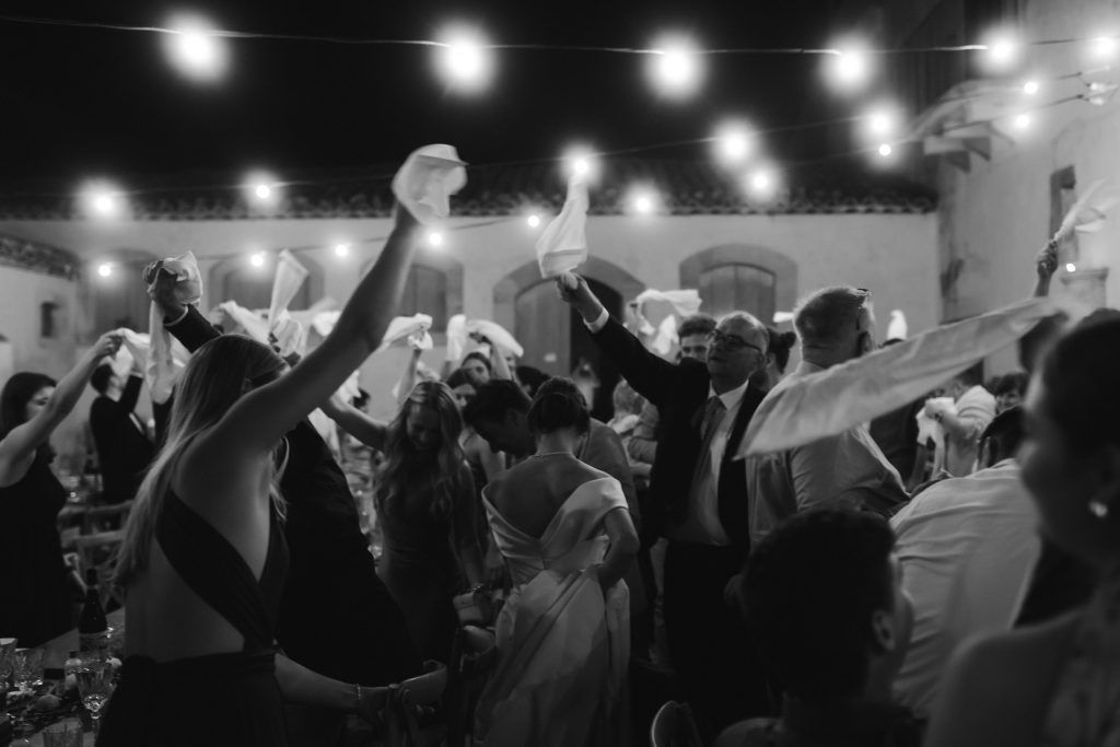 Gäste feiern Hochzeit auf Sizilien mit Servietten unter Lichterketten