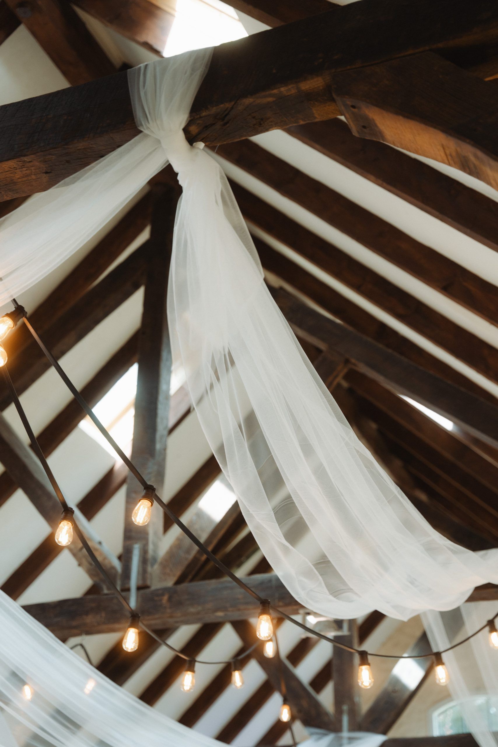 Holzbalkendecke im Schloss Grünewald mit Lichterketten und weißem Stoff dekoriert