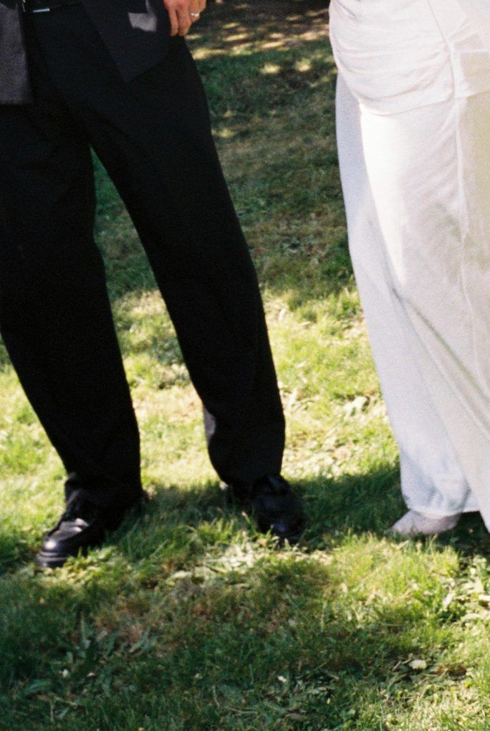 Detailaufnahme des Brautpaars im Hochzeitsoutfit bei einem Spaziergang im Grünen