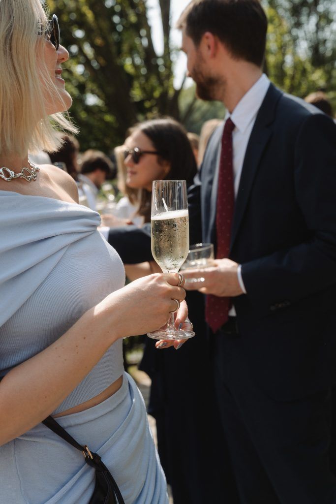 Hochzeitsgäste stoßen mit Sekt bei einer sommerlichen Feier gemeinsam an